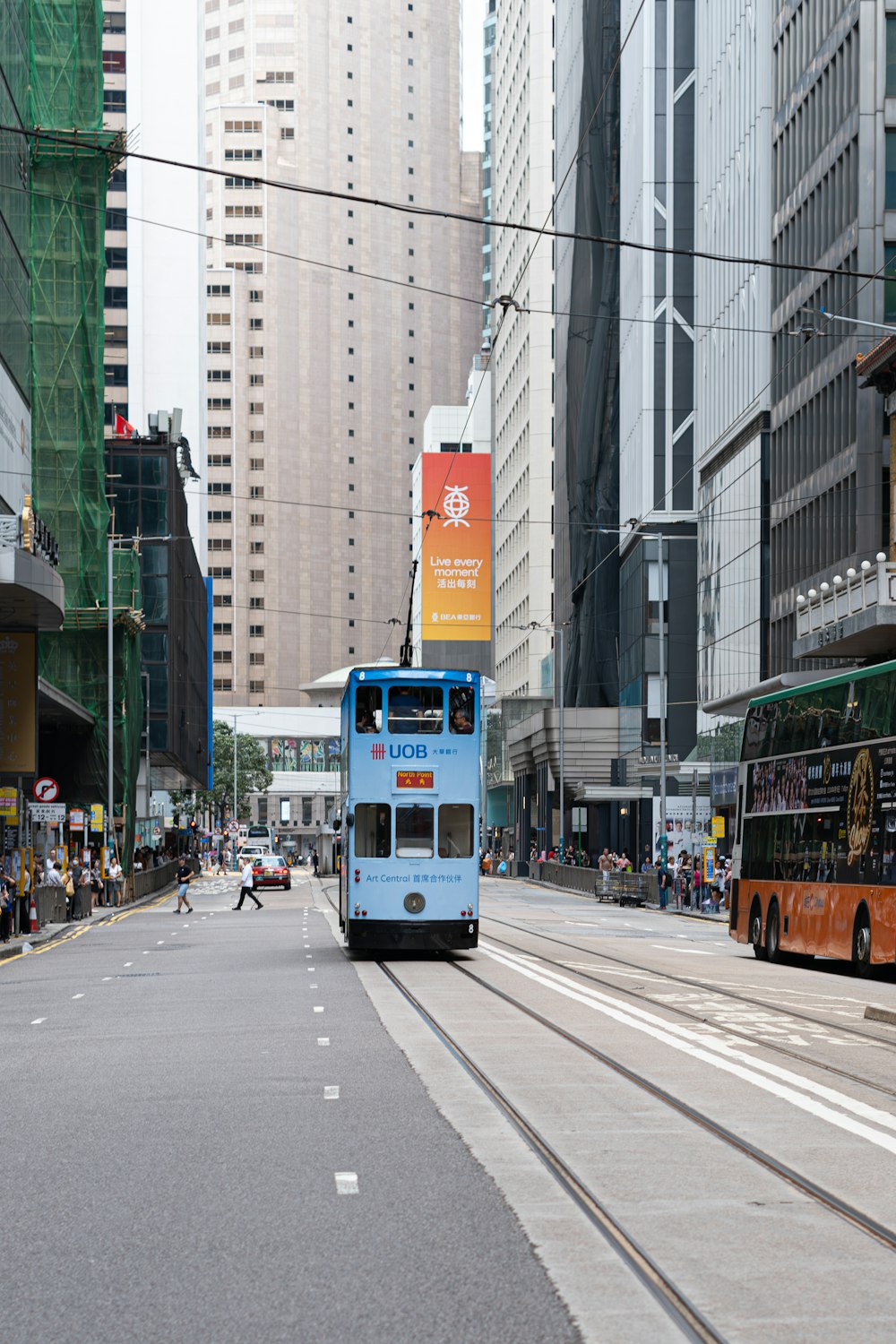 a blue double decker bus driving down a street next to tall buildings