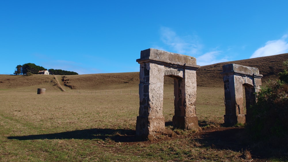 two stone pillars in a grassy field with a hill in the background