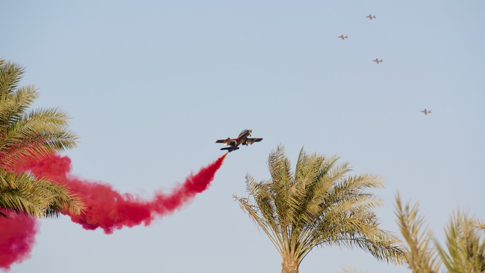a plane flying in the sky with red smoke coming out of it