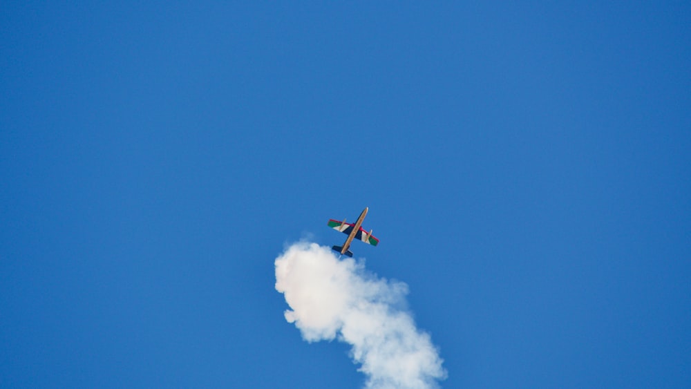 a small airplane flying through a blue sky