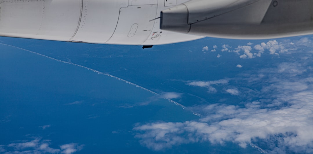 the wing of an airplane flying over the clouds, The image captures a close-up of an airplane