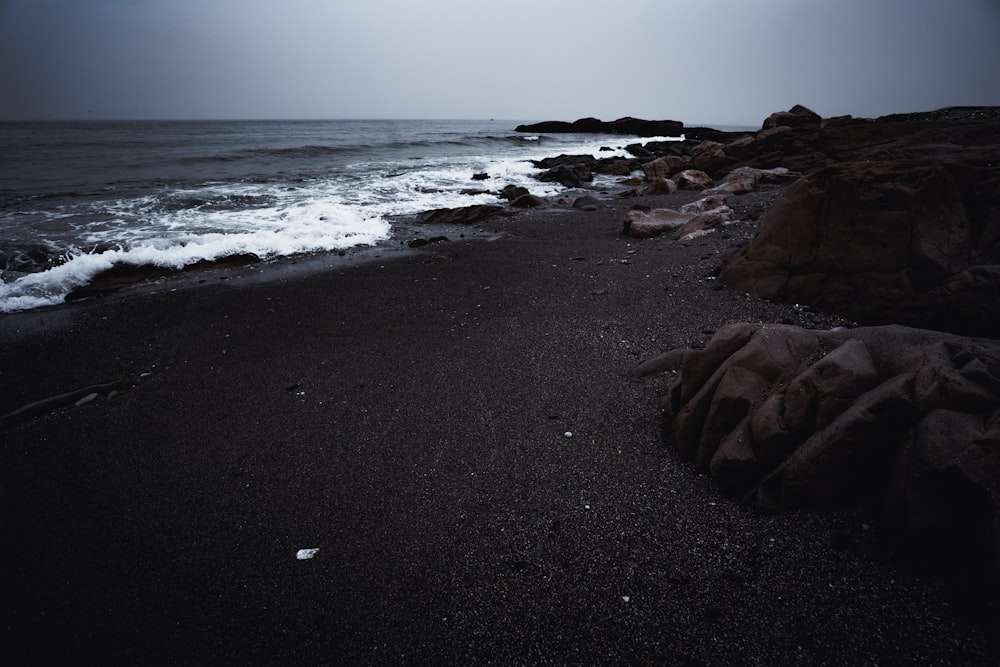 a dark beach with waves coming in to shore