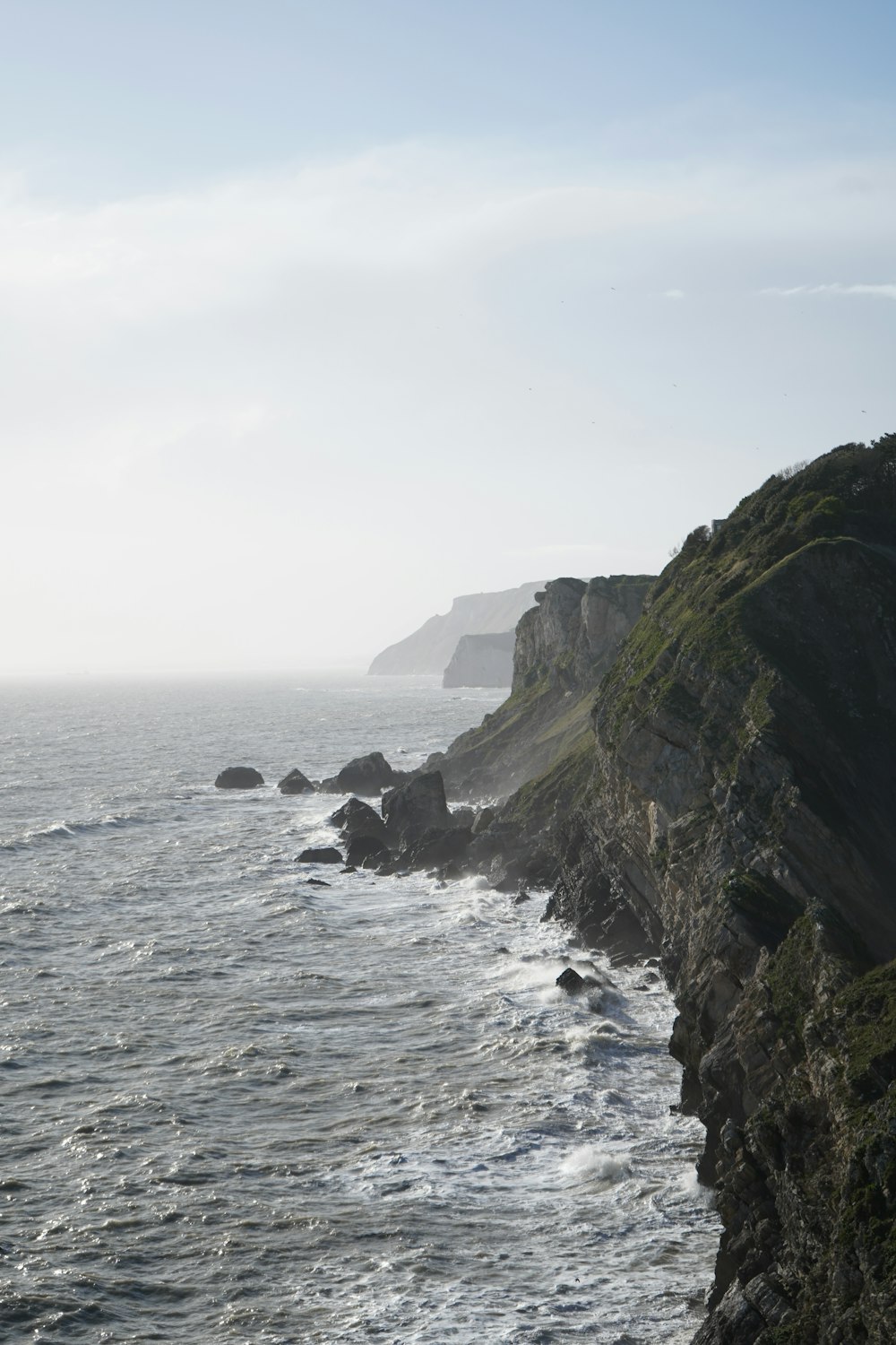 a rocky cliff overlooks the ocean on a foggy day