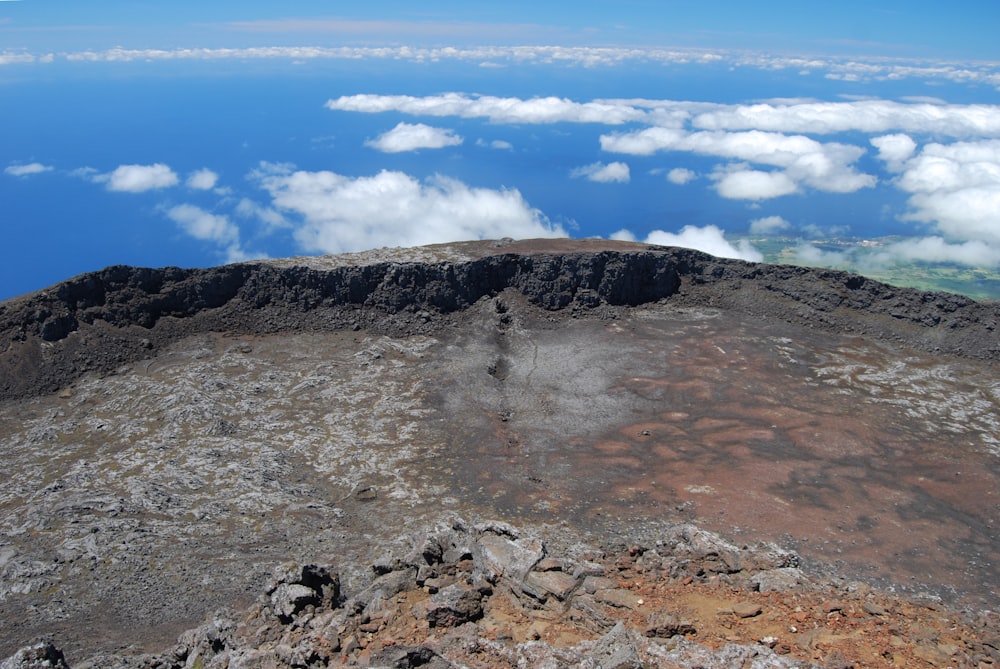 a view of the top of a mountain with clouds below