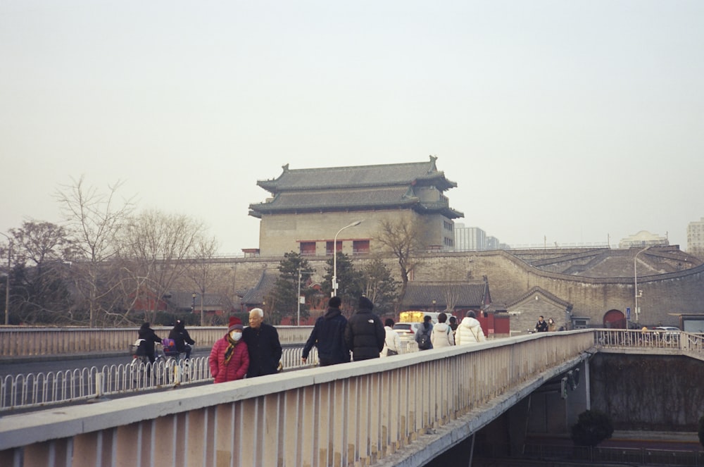 a group of people walking across a bridge