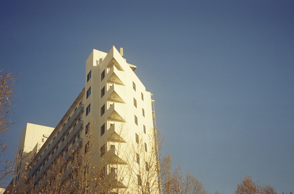 a tall white building with trees in front of it