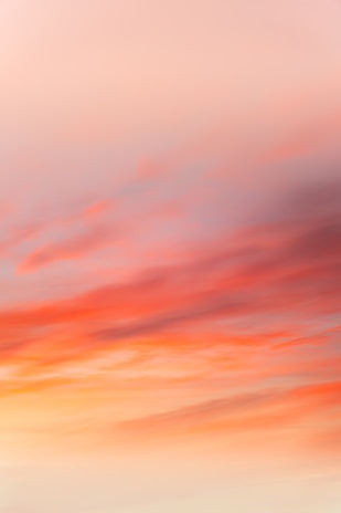 a red and orange sky with a plane flying in the distance