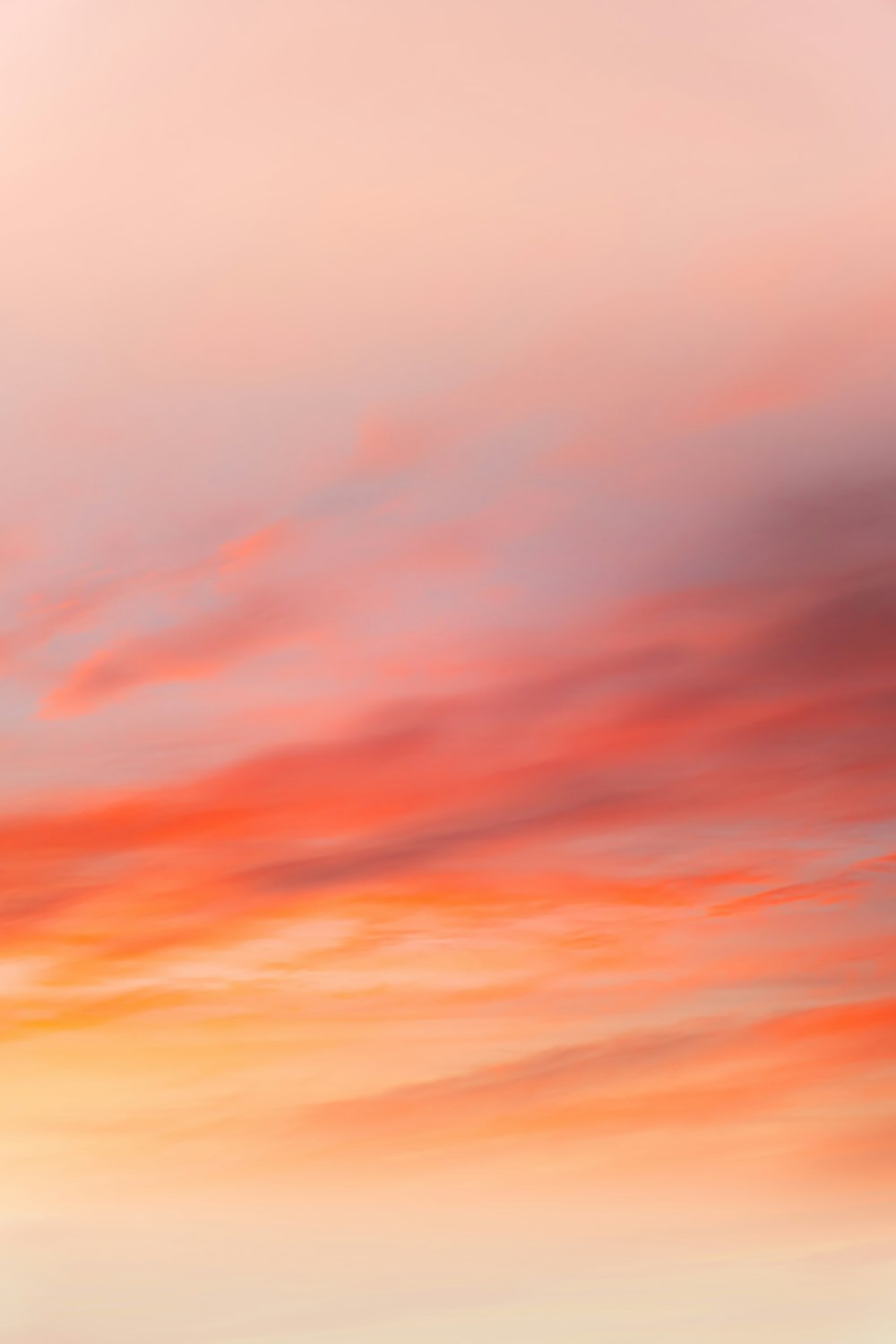 a red and orange sky with a plane flying in the distance