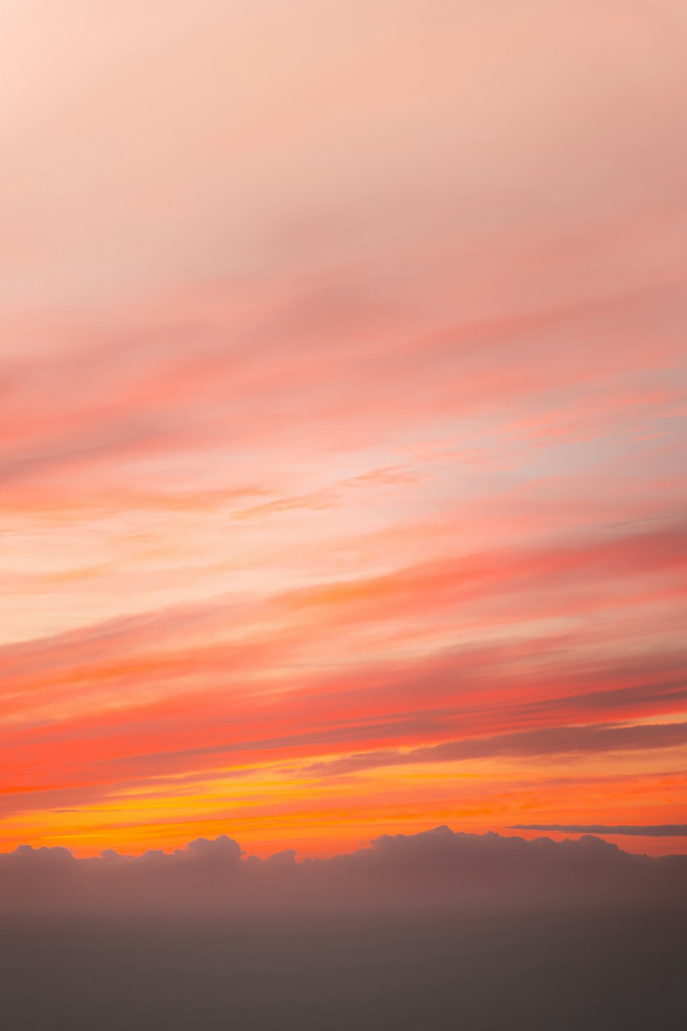 a plane flying in the sky at sunset