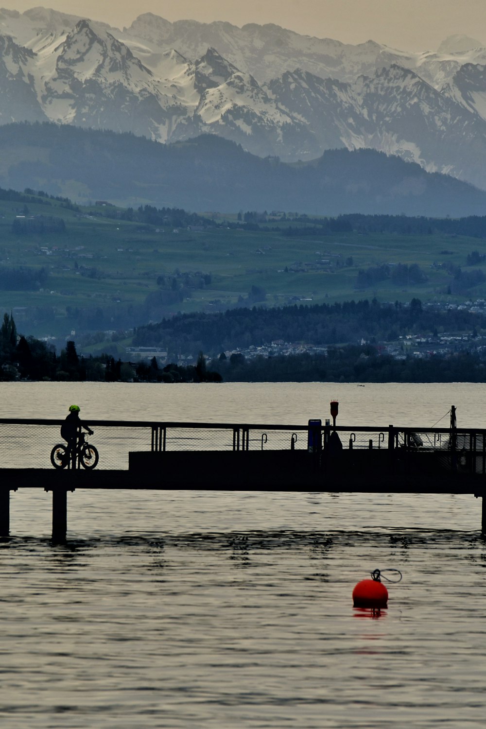 una persona montando una bicicleta en un puente sobre un cuerpo de agua