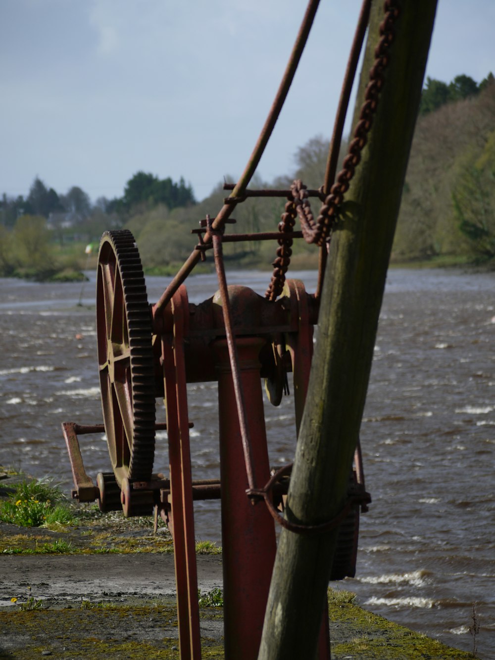 an old water pump sitting on the side of a river