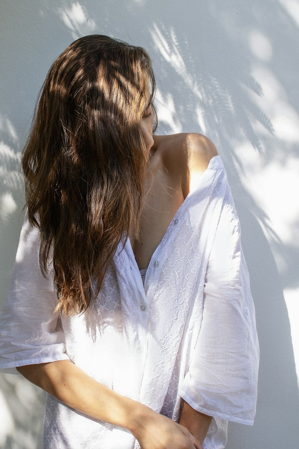 a woman in a white shirt leaning against a wall