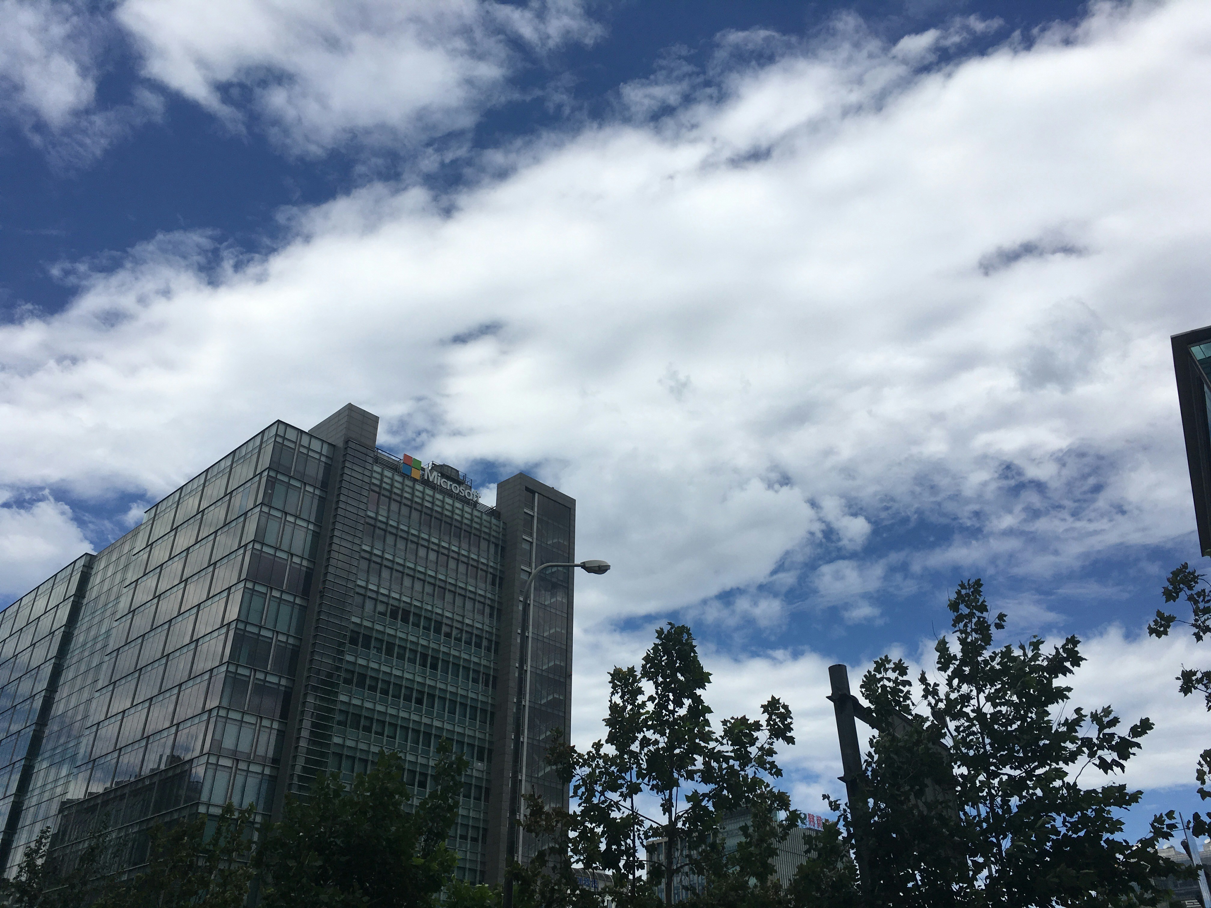 Microsoft logo on glass building exterior, blue sky reflection