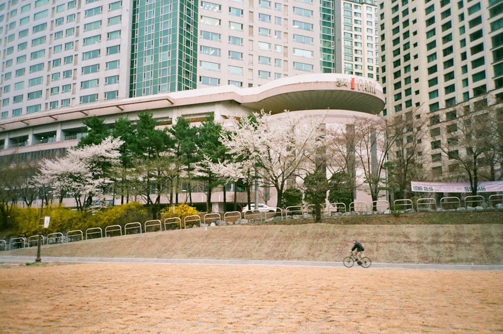 a person riding a bike in front of a large building