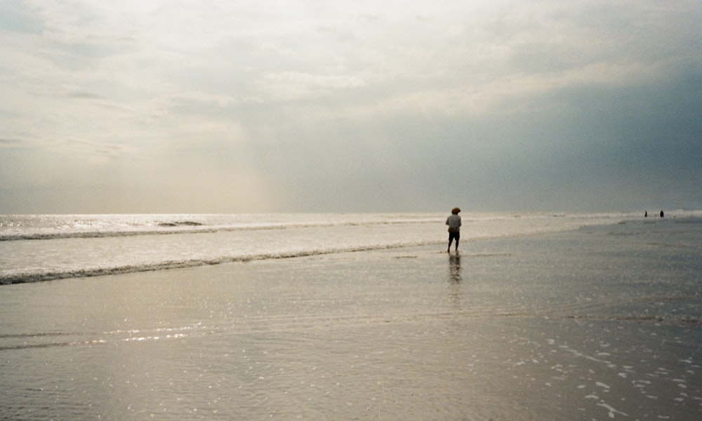 a person standing on a beach near the ocean