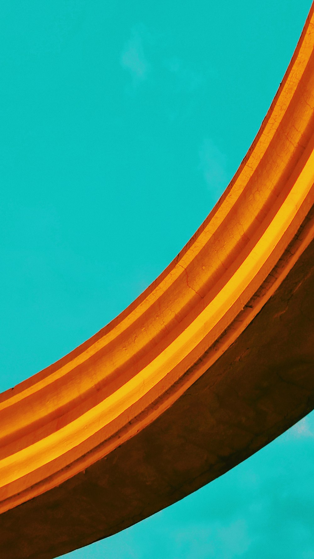 a close up of a curved metal object against a blue sky