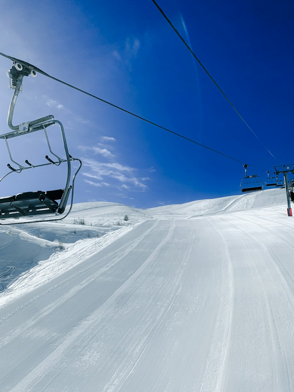 ein Skilift, der einen verschneiten Hügel hinaufführt