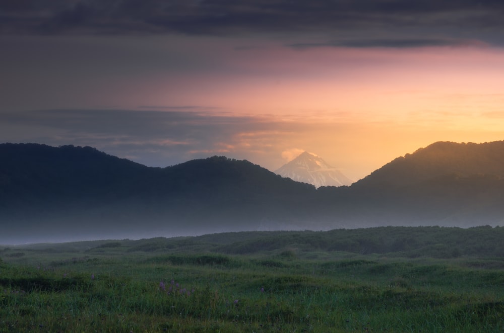 the sun is setting over a mountain range