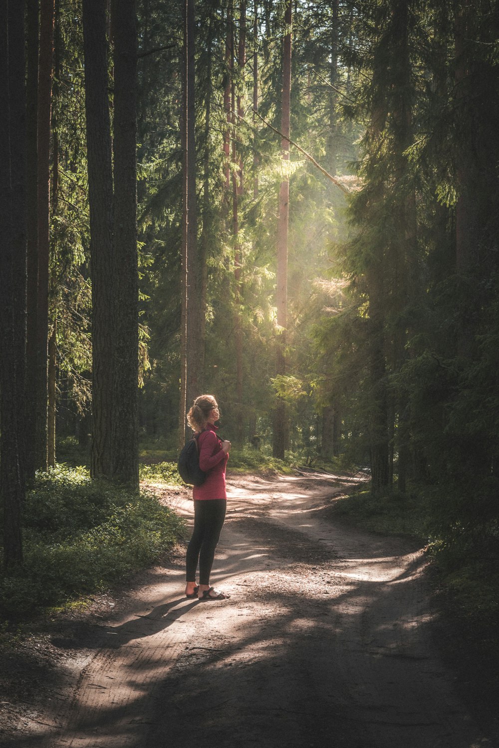 a woman running down a dirt road in the woods