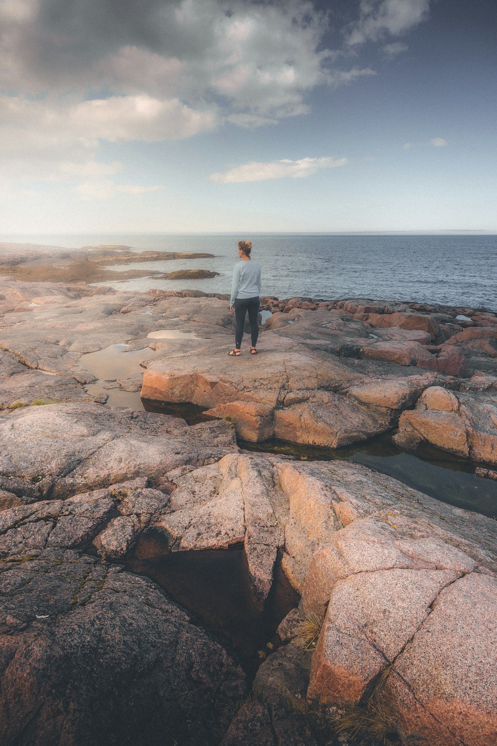 a person standing on a rocky beach next to the ocean