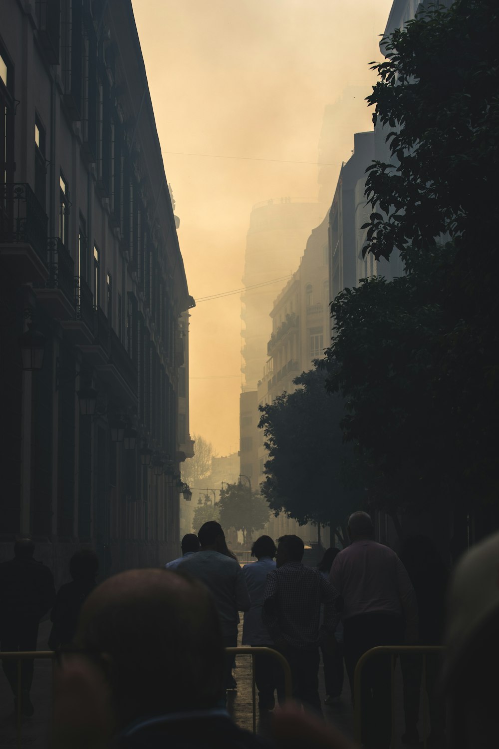 a group of people walking down a street next to tall buildings