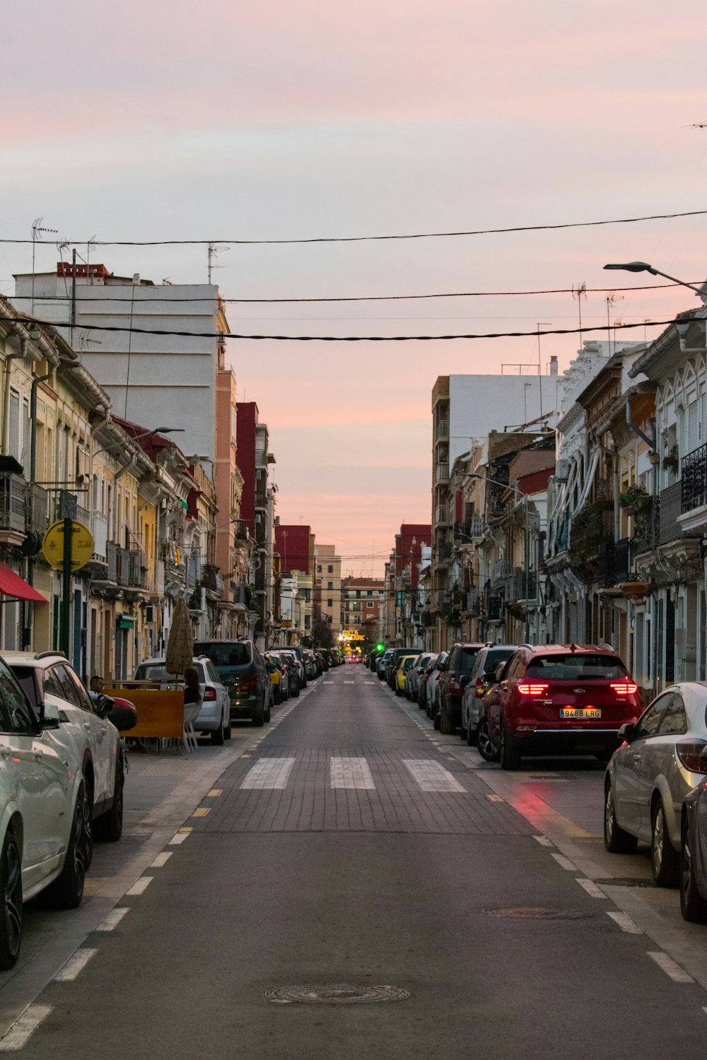 a street lined with parked cars next to tall buildings