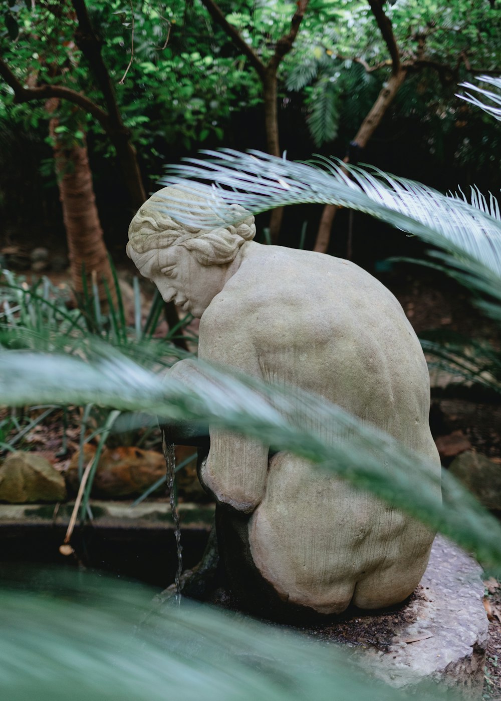 a statue of a woman sitting on top of a rock