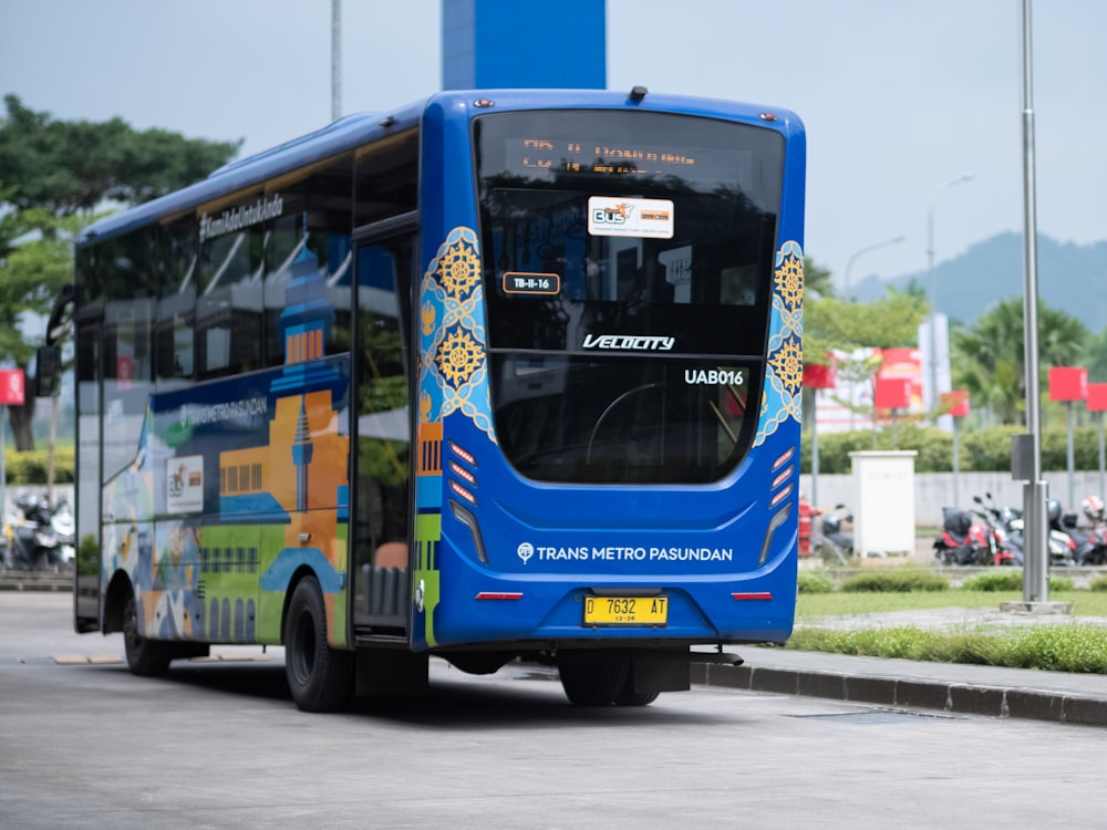 a blue bus driving down a street next to a tall building