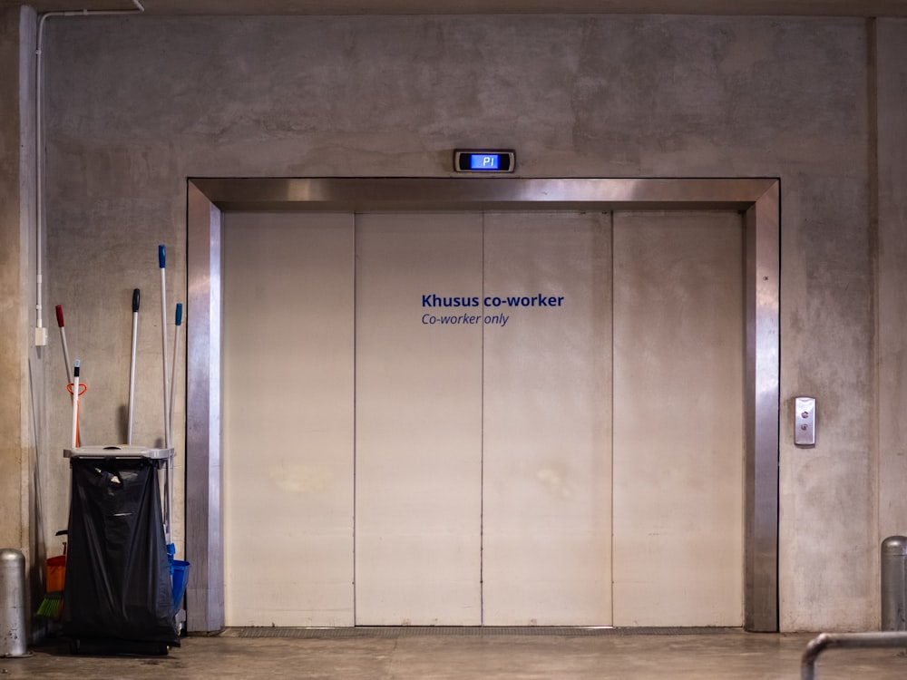 an elevator with a black trash can in front of it