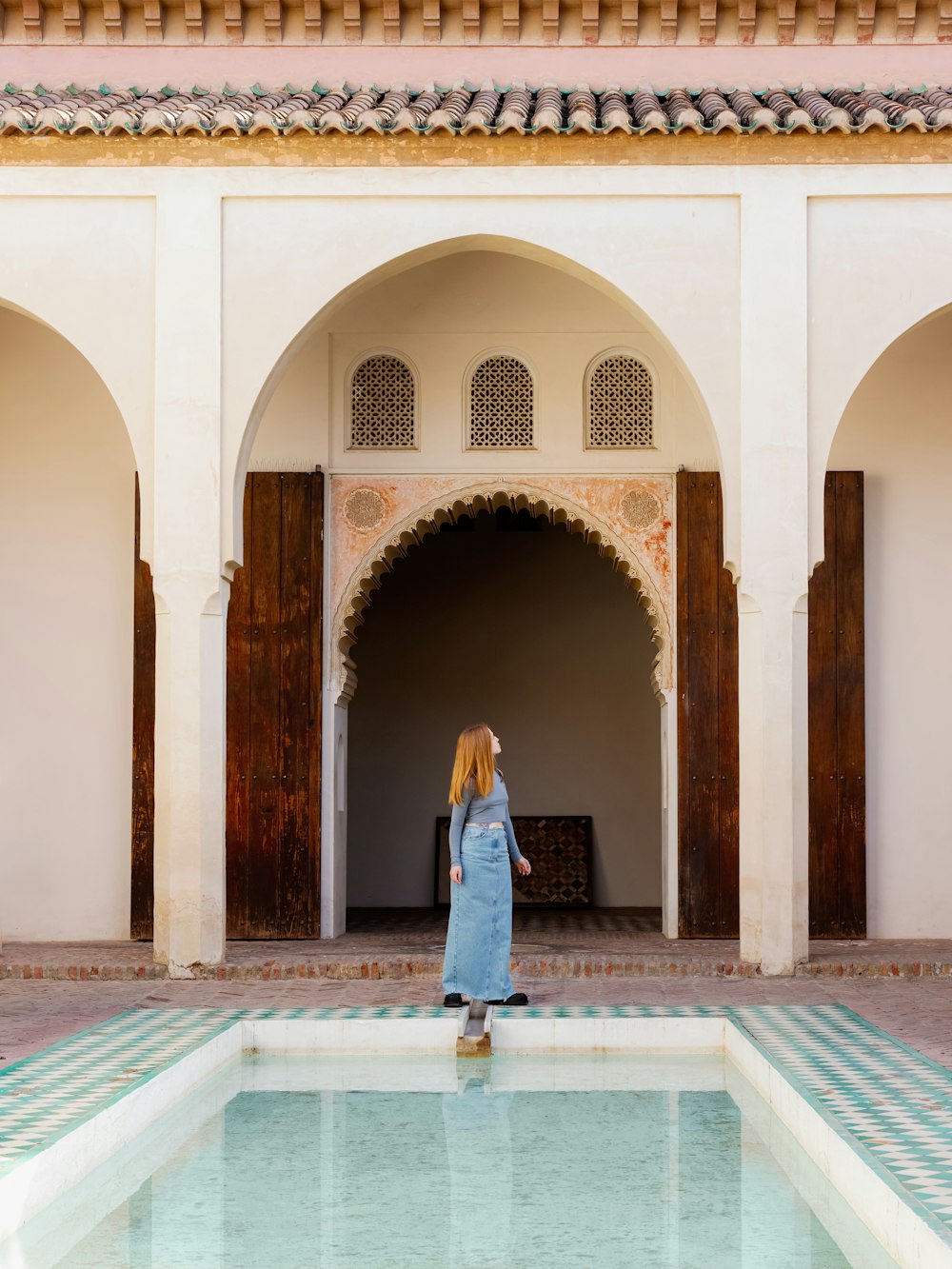 a woman in a blue dress standing in front of a pool