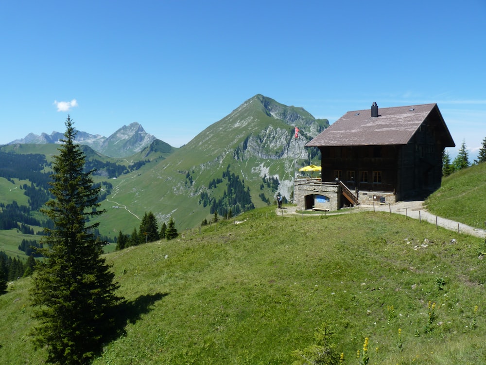 a small cabin on a grassy hill with mountains in the background