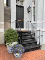 a black door and some flowers in front of a house