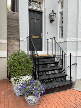 a black door and some flowers in front of a house