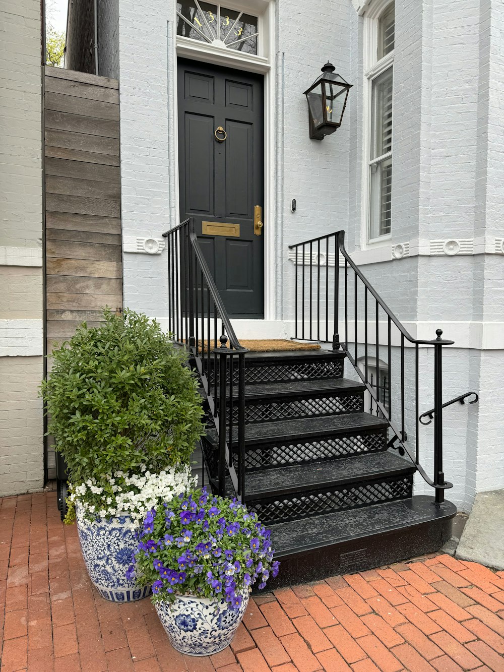 a black door and some flowers in front of a house