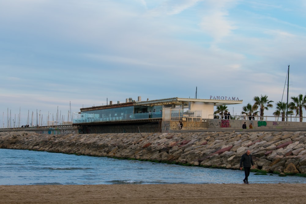 a man walking on a beach next to a body of water