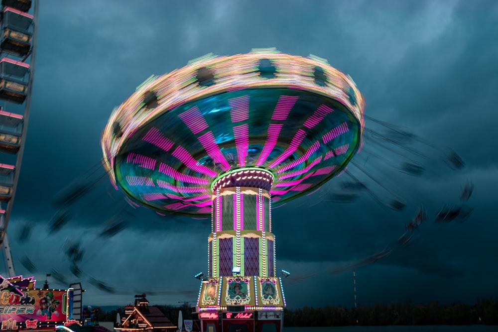 a carnival ride at night with a ferris wheel in the background