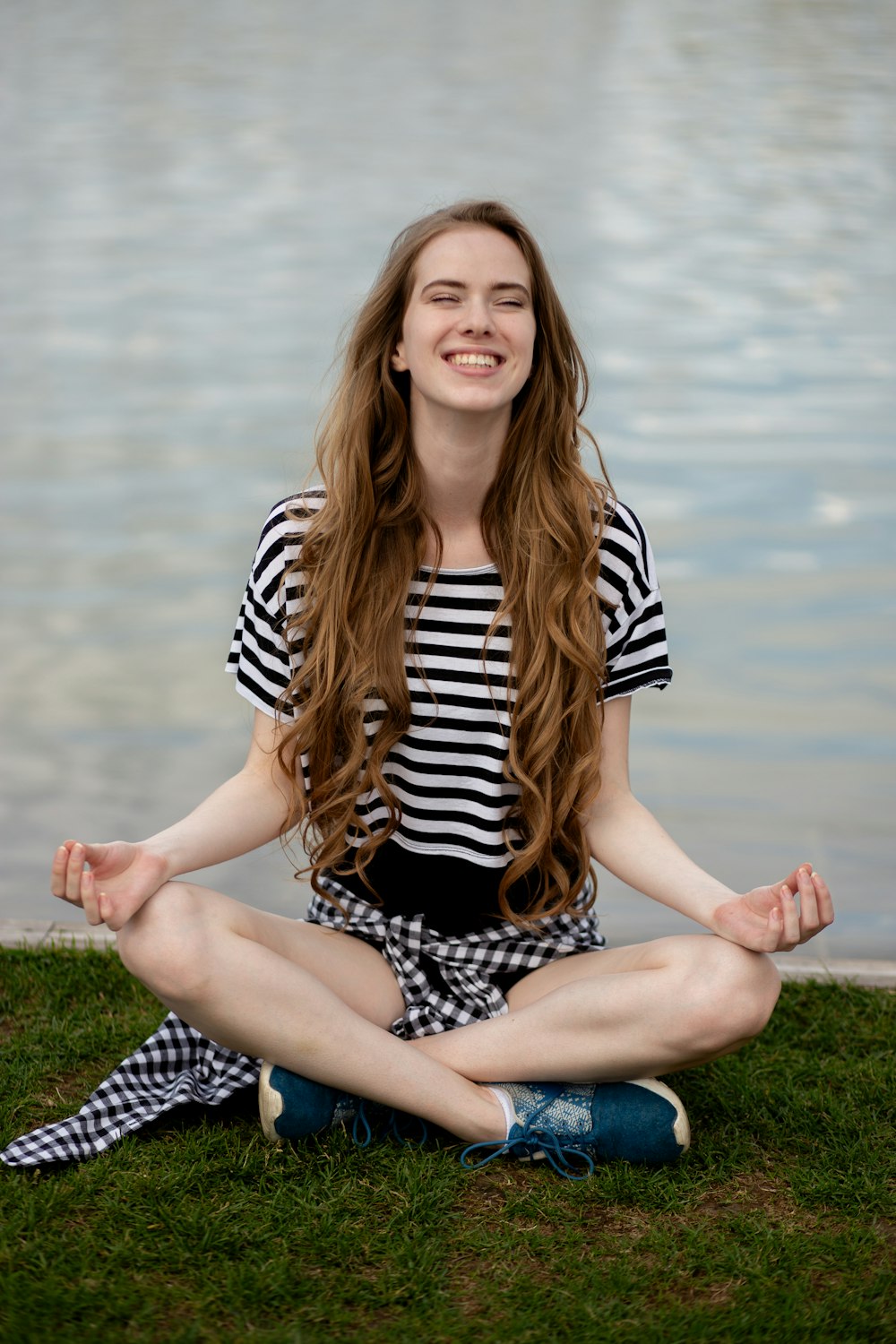 a woman sitting on the grass in a yoga pose