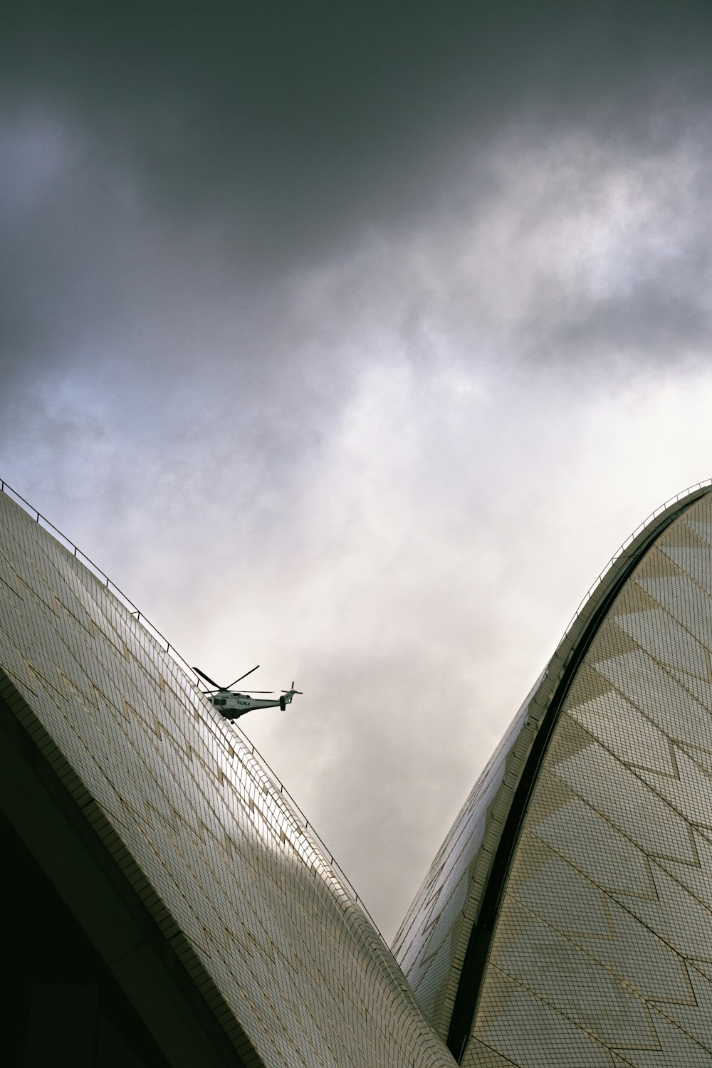 구름 낀 하늘 아래 건물 위를 날고 있는 비행기
