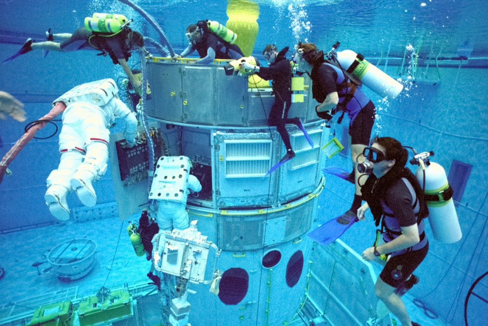 a group of people in scuba gear standing on a diving platform