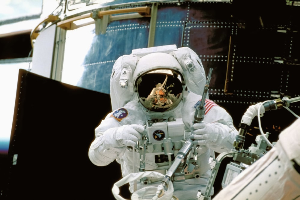 um homem de traje espacial parado em frente a uma estação espacial