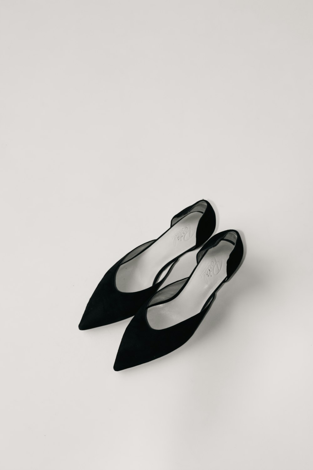a pair of black shoes sitting on top of a white surface