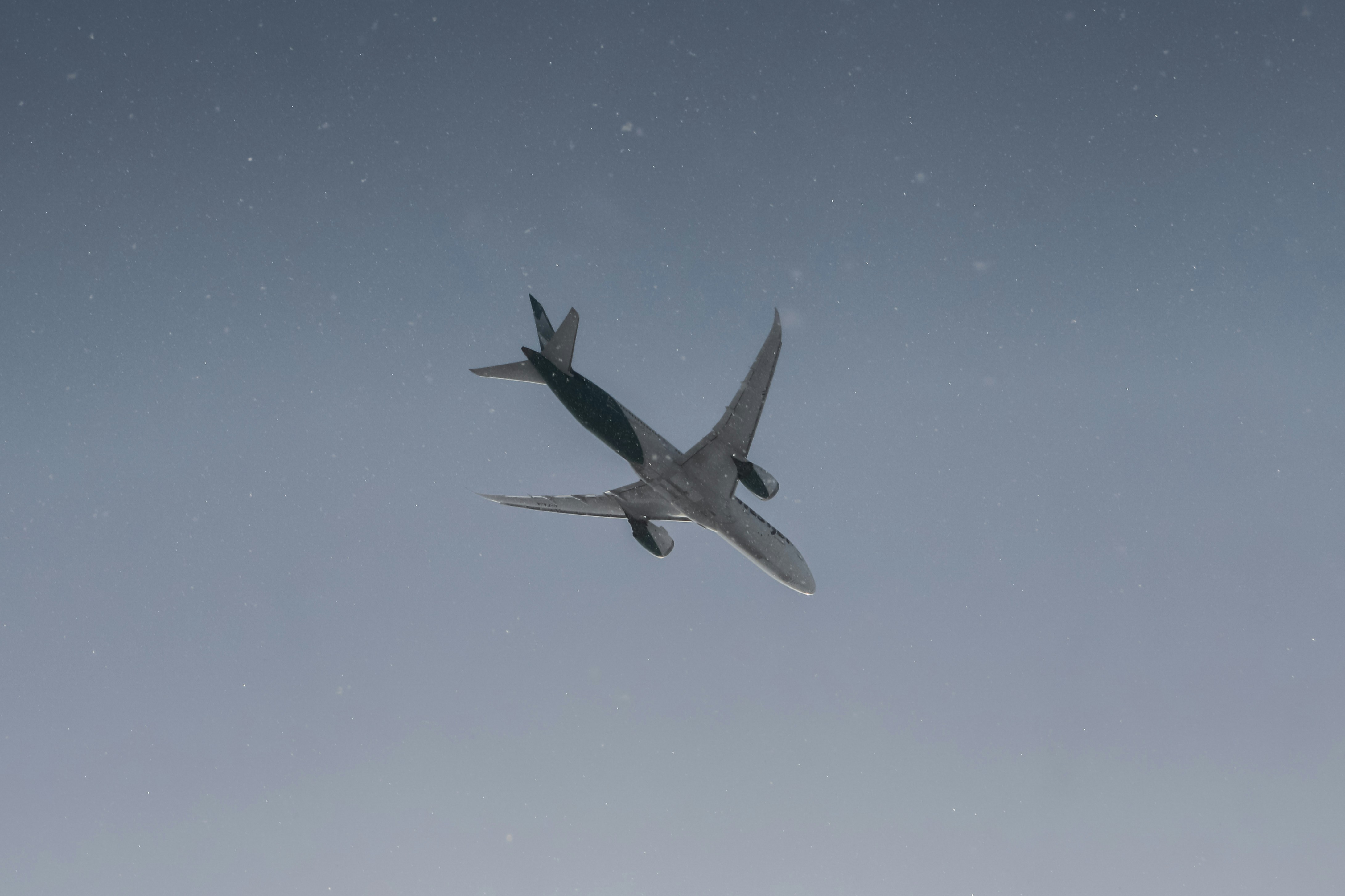 a large jetliner flying through a blue sky, Landing Airplane surrounded by lightly falling snow