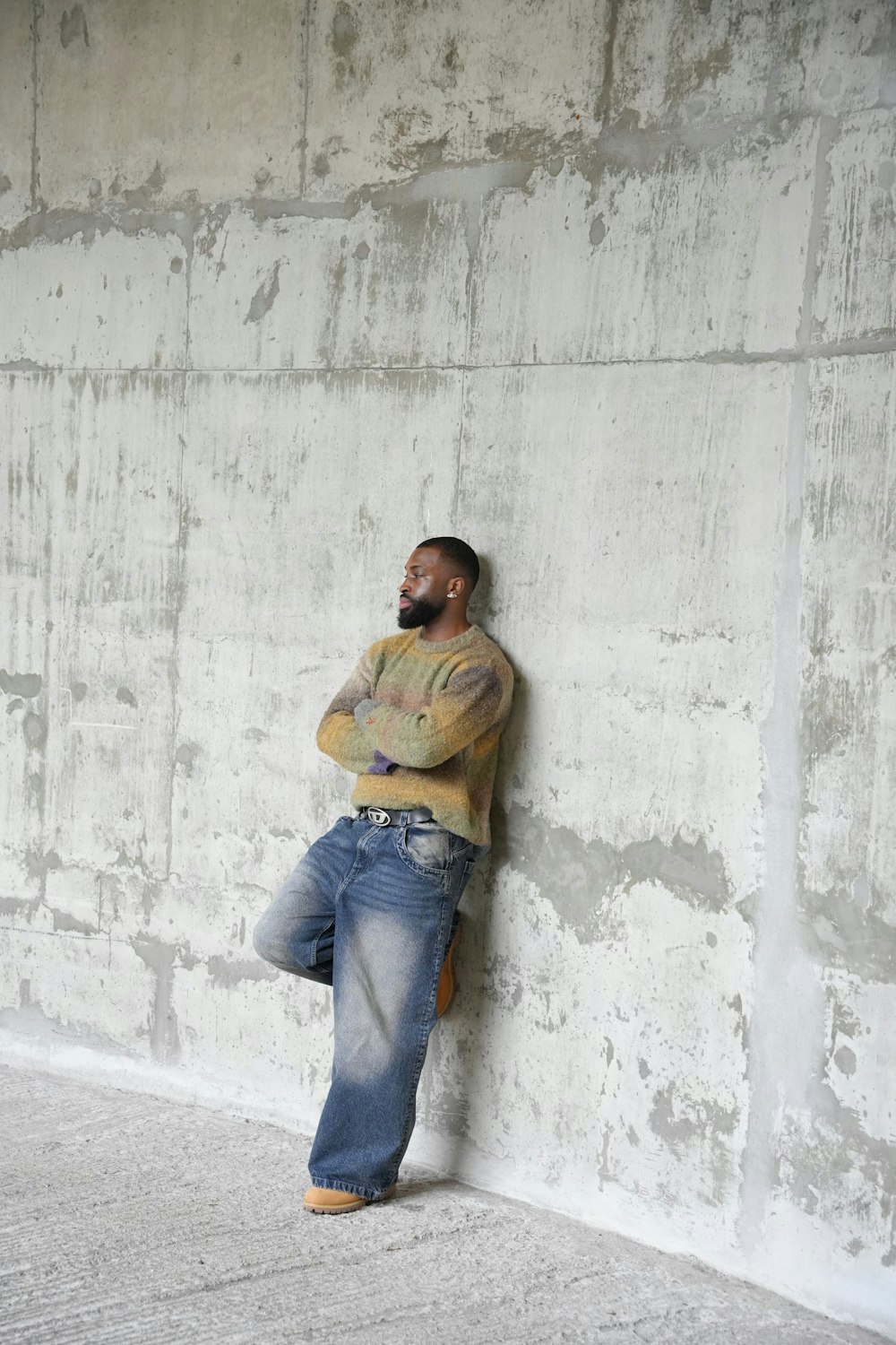 a man leaning against a wall with his arms crossed