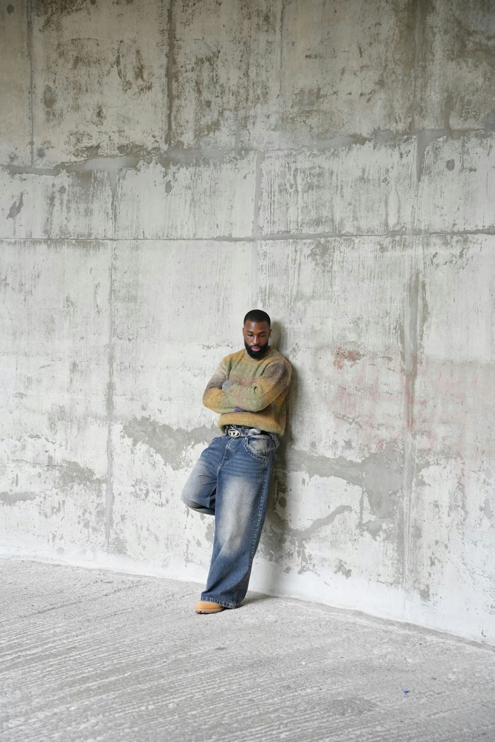 a man leaning against a wall with his arms crossed