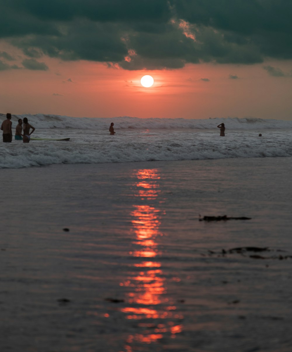 a group of people standing on top of a beach next to the ocean