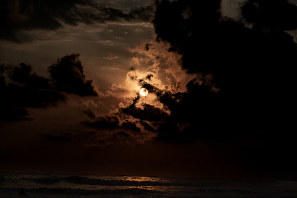 the sun is setting over the ocean on a cloudy day