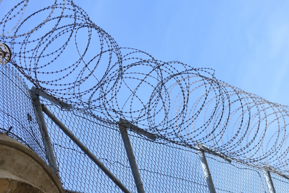 a fence that has a bunch of barbed wire on top of it