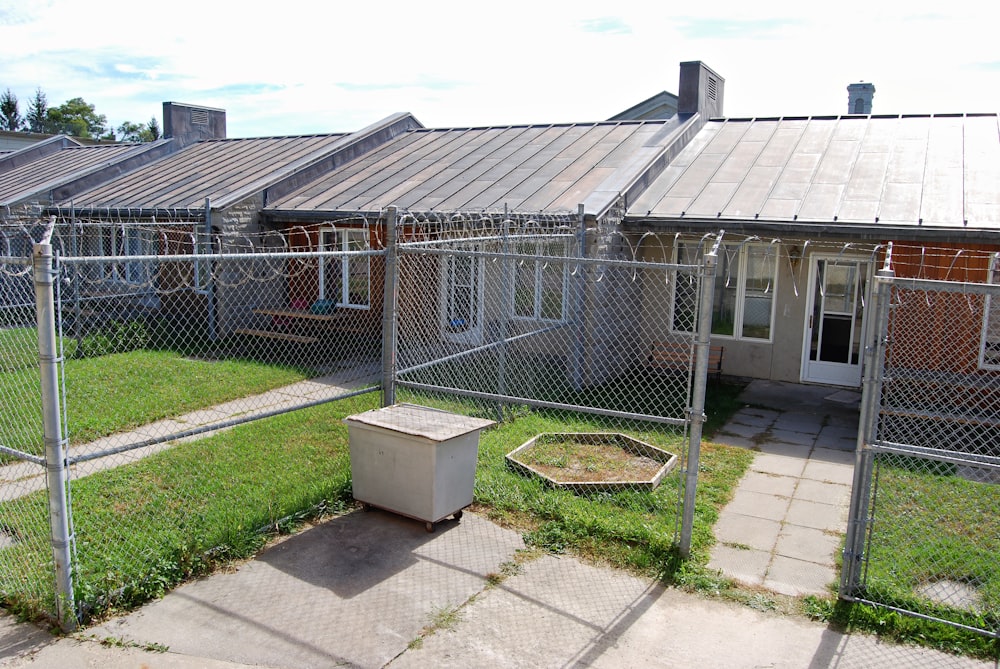 a fenced in yard with a trash can in front of a house