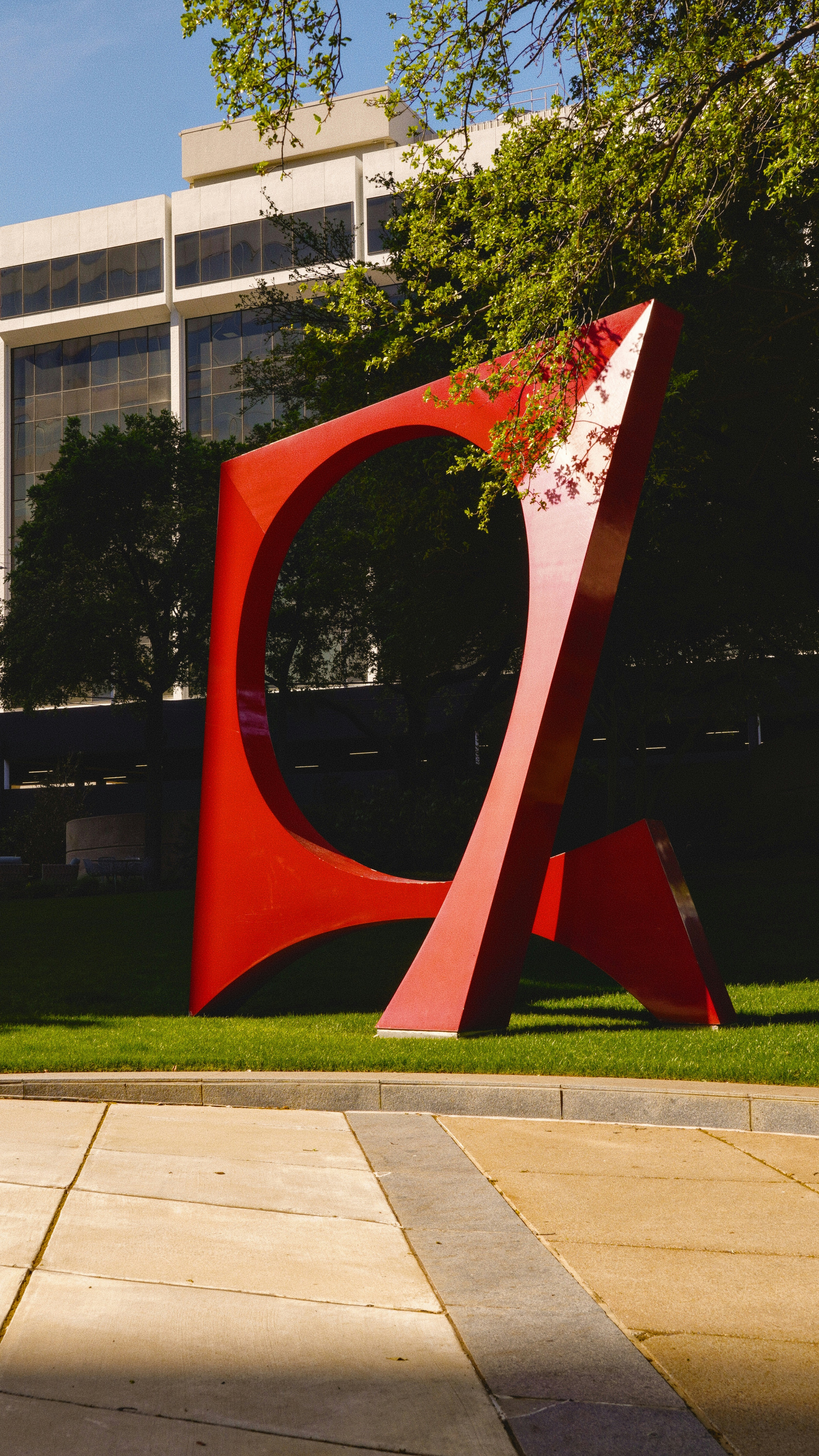 Large red abstract sculpture in a downtown Dallas park