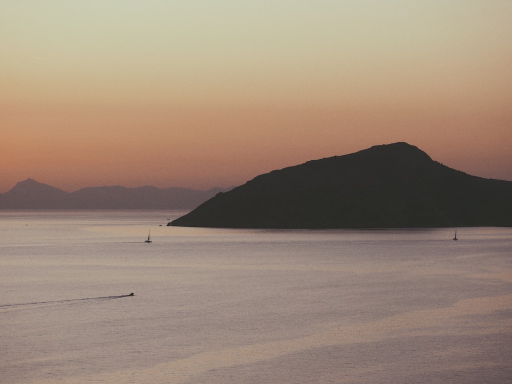 a large body of water with a mountain in the background